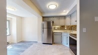 Located at 17 Regan St in Vernon Rockville, Connecticut, this single-floor residence offers a thoughtfully updated interior with a cohesive, modern design. The kitchen is a standout feature, showcasing gray raised-panel cabinetry, light granite-style countertops, a mosaic tile backsplash in warm earth tones, and a full suite of stainless steel appliances including a refrigerator, range, and dishwasher. Large-format tile flooring runs throughout the kitchen, which is set at a slightly elevated level, connected to the rest of the living areas by a few steps. The living spaces feature light gray wood-look vinyl plank flooring that extends seamlessly through the open layout, lending a clean and contemporary feel. An entry area provides a welcoming transition into the home, complete with an exterior door featuring a multi-pane window that brings in natural light. The bathroom is finished with matching large-format tile flooring, a modern wood-toned vanity with ample drawer storage, white countertop, and a baseboard heating unit. Throughout the space, neutral wall tones, textured ceilings, and recessed and flush-mount lighting contribute to a bright, move-in-ready environment. The floor plan, as seen in the dollhouse view, presents a practical and well-organized layout with clear sightlines between areas.