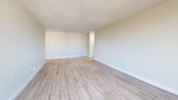 Located on the 9th floor at 105 Cherryhill Blvd in London, Ontario, this well-appointed one-bedroom unit offers a clean, modern living experience with thoughtful design throughout. The space is finished with light hardwood-style flooring that runs consistently across all rooms, complementing the neutral, soft grey-toned walls and crisp white trim for a bright, cohesive aesthetic.

The living room is a standout feature, boasting expansive floor-to-ceiling sliding glass windows that flood the room with natural light and frame sweeping views of the London skyline and surrounding greenery. Baseboard heating runs along the perimeter, ensuring year-round comfort. The open sightlines create a generous, airy atmosphere well-suited for both relaxing and entertaining.

The kitchen is positioned adjacent to the main living area, separated by a structural column that adds architectural character. It features white cabinetry with sleek metal hardware, a black electric range, and white countertops, providing ample functionality in a compact, efficient layout.

The generously sized primary bedroom offers a bright window with urban views, baseboard heating, and ample wall space. A hallway connects the bedroom to additional rooms, including a bathroom and closet area, ensuring a practical and well-organized flow. The unit's overall design is clean, minimal, and move-in ready.