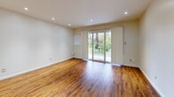 This efficient single-floor unit in Oakland, CA (94611) is thoughtfully laid out to maximize every inch of its compact footprint. The combined kitchen and living area serves as the heart of the space, where warm-toned hardwood flooring flows seamlessly throughout, creating a cohesive and inviting atmosphere. Recessed lighting illuminates the living area, complemented by natural light pouring in through a large sliding glass door that opens to a lush outdoor view featuring mature trees and a patio — a serene and inviting extension of the interior. The kitchen is well-equipped with light maple cabinetry offering ample storage, granite-style countertops, a stainless steel dishwasher, and an electric range, providing all the essentials in an organized and functional layout. A hallway connects the main living space to the bathroom, which features a full soaking tub with shower, brushed gold fixtures, marble-style tile flooring, and a vanity with wooden cabinetry — offering a clean, classic aesthetic. An additional room with a built-in closet provides flexible space for sleeping or storage. Clean white walls throughout keep the space feeling bright and open, making this a well-appointed unit ideally suited for comfortable everyday living.
