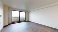 Located at 125 E 156th St in Cleveland, Ohio, this single-floor residential unit offers a clean, functional layout with consistent hardwood-style flooring throughout. The living area is bright and open, benefiting from a large sliding glass door that leads to a balcony and allows generous natural light to fill the space, along with views of the surrounding neighborhood. The room's neutral walls and textured ceiling contribute to a simple, welcoming ambiance.

The kitchen is efficiently designed, featuring warm honey-toned oak cabinetry both above and below the countertops, a white electric range, a stainless steel sink, and a refrigerator. Ample cabinet storage makes the kitchen practical for everyday use. An open passageway connects the kitchen to the rest of the unit, maintaining a sense of flow throughout.

A separate bedroom offers its own natural light through a standard window with outdoor views, and features the same hardwood-style flooring carried throughout the unit. The full bathroom is well-appointed with a dark-toned vanity with a white countertop and undermount sink, a full tub and shower combo with white tile surround, a mirrored medicine cabinet, and classic mosaic tile flooring. Overall, the unit presents a tidy, move-in ready space with a straightforward and practical design.
