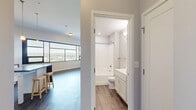 Located at 161 Concord Exchange in South Saint Paul, MN, this 2-bedroom, 3-bathroom residence offers a well-designed, single-floor layout with a clean, modern aesthetic throughout. The open-concept kitchen and living area serves as the heart of the home, featuring white shaker cabinetry, a mosaic tile backsplash, dark countertops, and a full suite of stainless steel appliances. A central island with a stone-look finish and bar seating provides additional prep and dining space. Warm-toned hardwood-style flooring runs throughout the main living areas, while pendant lighting above the island adds a stylish, contemporary touch. Large windows in both the kitchen and primary bedroom allow abundant natural light and frame open outdoor views of the surrounding landscape. The primary bedroom is a generously sized retreat with plush carpeting, and the second bedroom offers similarly comfortable, carpet-covered flooring with easy hallway access. Three bathrooms include a tub-shower combination with clean white surrounds and brushed nickel fixtures, as well as vanities with white cabinetry. Neutral gray tones on the walls create a cohesive and calming palette throughout the entire space, complemented by crisp white trim and modern door hardware.