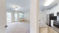 Located at 138 Inspiration Ave in Bluffton, SC, this well-appointed 2-bedroom, 2-bathroom single-floor residence offers a clean, bright, and functional layout. The living room is carpeted and bathed in natural light from large windows and a glass-paneled door that opens to a private balcony, complemented by a ceiling fan overhead. The kitchen features granite countertops, white cabinetry, and warm hardwood-style flooring, creating a practical yet polished space. Both bedrooms are carpeted and receive natural light through sizable windows fitted with blinds, each equipped with a ceiling fan. The primary bedroom is generously sized with direct access to its own bathroom. The bathrooms include tiled tub-shower combos and granite countertop vanities, maintaining a consistent design throughout. Closet space is provided in both bedrooms, with one featuring a walk-in style closet with built-in shelving and mirrored doors. A dedicated utility room with hardwood-style flooring houses the washer, dryer, and water heater. A hallway connects the spaces seamlessly, and neutral tones throughout lend the home a bright, airy ambiance suited to the Lowcountry setting.