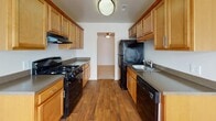 Located at 11307 Dunbrook Rd in North Chesterfield, Virginia, this single-floor home offers a thoughtfully arranged layout with a clean, neutral aesthetic throughout. The living area is generously sized, featuring plush wall-to-wall carpeting and a full-width sliding glass door dressed with vertical blinds that fills the room with natural light. An adjacent bedroom features its own large window with views of the surrounding greenery, continuing the bright and airy feel. A second bedroom includes a built-in closet with bifold doors and direct access to an entry door, providing added convenience and storage. The galley-style kitchen is well-equipped with warm honey-toned wood cabinetry, dark granite-style countertops, black appliances including a gas range and dishwasher, and durable wood-look flooring. A dining nook adjacent to the kitchen benefits from a pendant chandelier and a bright window. The primary bedroom connects directly to a bathroom, offering added privacy, while a second bathroom features rich wood vanity cabinetry, a dark stone countertop, a large mirror, and hardwood-style flooring. The space presents a practical, comfortable layout suited for everyday living.
