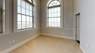 This single-floor unit combines classic architectural details with modern finishes throughout its well-appointed layout. The bedroom is a standout space, characterized by soaring ceilings and dramatic arched windows topped with elegant fanlight transoms. These oversized windows flood the room with abundant natural light and offer views of the surrounding streetscape. Neutral-toned carpet and paneled wall moldings lend a refined, traditional character to the space.

The living area continues the bright, open feel with large multi-pane windows, warm hardwood-style flooring, and elevated ceilings fitted with recessed and pendant lighting. A louvered closet provides practical storage, while the open-plan layout connects seamlessly to the kitchen.

The kitchen is equipped with dark espresso cabinetry, dark granite countertops, and black appliances including a refrigerator, range, and built-in microwave. A peninsula with an integrated stainless steel sink and pendant lighting above creates a functional and stylish focal point.

The bathroom features slate-toned tile flooring, a pedestal sink, a tub-shower combination, and a bright window that allows natural light. A dedicated laundry area with washer and dryer hookups and a carpeted walk-in closet complete this well-designed unit.