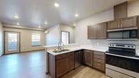 Located at 3027 E Upriver Dr in Spokane, WA, this well-appointed one-bedroom, one-bathroom unit offers a thoughtfully designed layout across a single floor. Light-toned luxury vinyl plank flooring flows throughout, lending a clean, cohesive aesthetic to every room.

The open-concept kitchen and living area serves as the heart of the unit. The kitchen is outfitted with rich, dark-stained cabinetry, crisp white countertops, and a full suite of stainless steel appliances, including a range, microwave, dishwasher, and refrigerator. A peninsula with a double-basin sink provides both prep space and a natural divide between the kitchen and living area. Recessed lighting keeps the space bright and functional.

The living room benefits from large windows and a glass-panel door that opens to a private balcony, flooding the space with natural light and offering pleasant outdoor views. A wall-mounted mini-split unit ensures year-round climate comfort.

The bedroom is a well-sized retreat, also equipped with its own mini-split system for individualized temperature control and a closet for storage.

The bathroom features a dark wood vanity with a wide mirror and modern light fixture. Adjacent to the bathroom, a dedicated closet houses a full-size washer and dryer, adding exceptional in-unit convenience.