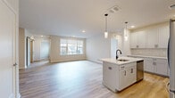 Located at 8000 Crescent Cir in Randolph, NJ, this well-appointed single-floor residence offers a thoughtfully designed open-concept layout across a generous footprint. The combined kitchen and living room serves as the heart of the home, showcasing light hardwood-style flooring, recessed lighting, and a large window that fills the space with natural light. The kitchen features a central island with an undermount sink, crisp white shaker cabinetry with matte black hardware, a white subway tile backsplash, quartz countertops, and stainless steel appliances including a Whirlpool range, over-the-range microwave, and refrigerator. Pendant lighting above the island adds a refined touch. A separate dining room and a versatile den provide additional living and flex space. The primary bedroom is generously sized with an outdoor view, while both bedrooms feature light-toned hardwood-style flooring. The bathrooms are finished with wood-look tile in the walk-in shower, marble-style floor tile, and warm wood cabinetry. Four closets, including a walk-in with built-in shelving systems, offer exceptional storage. A dedicated laundry room and utility room complete this functional and modern home.