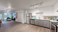 This well-appointed 3-bedroom, 4-bathroom single-story residence offers a thoughtfully designed layout with hardwood-style flooring flowing throughout. The open-concept kitchen is a standout feature, showcasing white upper cabinetry, gray lower cabinets, light countertops, stainless steel appliances including a refrigerator, dishwasher, and range, and track lighting overhead. The kitchen opens seamlessly toward the living area, which is bright and inviting, featuring a ceiling fan, large windows, and a glass door leading to a private balcony with outdoor views. The bedrooms are generously proportioned, each equipped with ceiling fans and ample closet space — including mirrored sliding-door closets in select rooms. The spacious primary bedroom offers room to comfortably accommodate a full furniture arrangement. The bathrooms are well-finished, with one featuring a double-sink vanity with warm wood cabinetry, white countertops, and a large mirror, while another includes a tiled tub-shower combination. With six closets throughout, storage is abundant. The home's clean white walls, consistent flooring, and neutral palette create a cohesive and modern ambiance, making it a comfortable and functional living space.