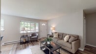 Located at 4676 Albany Post Rd in Hyde Park, NY, this well-appointed single-floor residence offers a thoughtfully designed layout with a clean, modern aesthetic throughout. The living room serves as the heart of the home, featuring light wood-style flooring, neutral warm-gray walls, and a front entry door with a decorative transom window that fills the space with natural light. Large windows frame views of the surrounding greenery, creating a welcoming and airy atmosphere.

The galley-style kitchen is efficiently organized with white cabinetry, granite-look countertops, a stainless steel sink, and white appliances, all set atop neutral tile flooring. A hallway connects the main living areas to the private quarters of the home.

The primary bedroom is generously sized, showcasing wood-style flooring, a window overlooking the wooded landscape, a dedicated closet, and ample room for full bedroom furnishings. A second bedroom offers similar flooring and a bright window, making it well-suited as a guest room, home office, or additional sleeping space.

The full bathroom is finished with light tile flooring and features a tub and shower combination with a tiled surround. Throughout the unit, consistent neutral tones and clean finishes contribute to a cohesive, move-in ready feel.