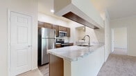 Located at 1500 Royal Gold Dr in Columbus, Ohio, this single-floor residence offers a well-designed layout with functional living spaces and modern finishes throughout. The kitchen serves as a central highlight, featuring a peninsula with elegant marble-look countertops, a stainless steel sink, rich warm-toned cabinetry, and a full suite of stainless steel appliances including a refrigerator, electric range, and microwave. Wood-look flooring in the kitchen and adjacent areas adds warmth and durability, while recessed lighting and a striking ceiling soffit detail contribute to the space's architectural character. The open layout connects the kitchen seamlessly to the carpeted living area, which is outfitted with a ceiling fan. The bedrooms are generously sized, each with plush carpet, ceiling fans, and six-panel doors. The primary bedroom enjoys natural light from a large window and includes access to a walk-in closet with wire shelving. The bathrooms are clean and practical, featuring wood-look flooring, warm cabinetry, soaking tubs with tiled surrounds, and ample overhead storage. A dedicated laundry room houses a full-size GE washer and dryer alongside a water heater, providing in-unit convenience. The overall ambiance is bright, neutral, and move-in ready.