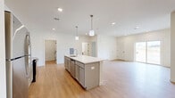 Located at 15 Ore Bank Rd in Dillsburg, PA, this single-floor home offers a thoughtfully designed layout across a comfortable footprint. The interior features a clean, modern aesthetic with neutral tones, light hardwood-style flooring in the main living areas, and plush carpet in the bedrooms.

The open-concept kitchen and living room serve as the heart of the home. The kitchen is outfitted with gray shaker-style cabinetry, white quartz countertops, stainless steel appliances including a range, microwave, and refrigerator, and a central island with a built-in sink and pendant lighting above. The living area extends from the kitchen and features recessed lighting and a sliding glass door that brings in natural light and outdoor views.

The generously sized primary bedroom provides ample space, while the two additional bedrooms feature carpeted floors and windows with natural light. One bedroom includes light hardwood-style flooring and a louvered closet door. The two bathrooms maintain the home's consistent style, featuring gray vanity cabinetry, white countertops, and light hardwood-style flooring. One bathroom includes a walk-in shower, while the other offers a tub-shower combo.

A dedicated laundry room with included washer and dryer units completes the home's functional layout.
