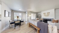Located at 7803 W Deschutes Ave in Kennewick, WA, this well-appointed single-floor unit offers 1 bedroom, 2 bathrooms, and a dedicated office across a thoughtfully laid-out floor plan. Light-toned luxury vinyl plank flooring runs throughout, complementing the neutral color palette that lends a bright, cohesive feel to every room.

The open-concept living and dining area is a standout feature, anchored by a tile-surround fireplace and large windows dressed with white linen curtains and slatted blinds that invite natural light while maintaining privacy. The kitchen features white shaker cabinetry, dark countertops, stainless steel appliances including a dishwasher, and a window above the sink overlooking greenery.

The primary bedroom is a comfortable retreat with a window framing outdoor views, light wood flooring, and ample space. Both bathrooms are cleanly finished with white vanity cabinetry and dark countertops. The dedicated office provides a quiet, windowed workspace with room for a full desk setup. A hallway and closet complete the layout, adding practical storage. The overall ambiance is modern and welcoming, with consistent finishes that make every area feel intentional and move-in ready.