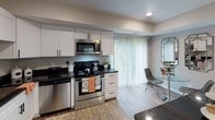 This two-floor residence offers a thoughtfully designed layout with a cohesive neutral color palette and wood-look flooring that flows throughout the main living areas. The living room features a tray ceiling detail with subtle ambient lighting, a large window fitted with horizontal blinds that invites natural light, and ample space for comfortable seating arrangements.

The kitchen is outfitted with crisp white shaker-style cabinetry, dark granite countertops, and a full suite of stainless steel appliances, including a range, microwave, dishwasher, and refrigerator. A sliding glass door with vertical blinds connects the kitchen to a dining area, which accommodates a generously sized table suited for gatherings.

The bedrooms are carpeted and well-proportioned, offering a quiet, restful atmosphere. A dedicated laundry room with hardwood-style flooring houses a full-size washer and dryer alongside a utility sink, providing added convenience. The bathroom is finished with a dark wood vanity, a wide mirror, and a glass-enclosed walk-in shower. Throughout the space, a warm and welcoming ambiance is maintained by consistent finishes, balanced lighting, and a clean, modern aesthetic.