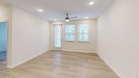 Located at 100 Southern Vine St in Moncks Corner, SC, this well-appointed 2-bedroom, 2-bathroom residence offers a thoughtfully designed single-floor layout with modern finishes throughout. The open-concept kitchen and living area serves as the heart of the home, anchored by a large center island with granite countertops and a built-in sink illuminated by three stylish pendant lights. White shaker cabinetry lines the walls, complemented by a full suite of stainless steel appliances including a refrigerator, range, and built-in microwave. Light wood-style plank flooring flows seamlessly through the main living areas, enhancing the bright and airy atmosphere. Both bedrooms feature plush carpeting, ceiling fans, and multiple windows dressed with blinds that invite ample natural light. The primary bedroom is a comfortable retreat with direct access to a dedicated closet outfitted with multi-tiered wire shelving systems for generous storage. The bathrooms are clean and modern, with one featuring a glass-enclosed walk-in shower with built-in shelving and brushed nickel fixtures. The overall design aesthetic is neutral and contemporary, with crisp white walls and consistent finishes that create a cohesive, move-in-ready environment.