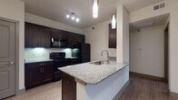 This single-floor, 2-bedroom, 2-bathroom residence on Jones offers a cohesive modern design throughout. The kitchen serves as a central highlight, featuring rich dark espresso cabinetry, granite countertops, a subway tile backsplash, and black appliances including an electric range, over-the-range microwave, and refrigerator. A peninsula with an undermount sink and pendant lighting above creates a natural transition into the open living area, which features light wood-style flooring for a clean, contemporary aesthetic.

Both bedrooms are carpeted for comfort and receive natural light through blinded windows. One bedroom includes a built-in granite-topped desk, offering a dedicated workspace. Ceiling fans are present in the bedrooms, adding practicality. The two bathrooms mirror each other in design, each featuring dark cabinetry with brushed nickel hardware, granite vanity surfaces, wood-style tile flooring, and a tiled tub-shower combination. The overall palette of neutral walls, dark cabinetry, and light flooring creates a balanced and modern ambiance throughout the space.