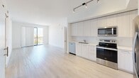 This contemporary apartment in Boca Raton, FL offers 1,010 square feet of thoughtfully designed living space. The open-concept layout showcases a sleek kitchen with white cabinetry, stainless steel appliances, and track lighting, seamlessly flowing into the living area. Light wood-look flooring runs throughout, complementing the crisp white walls and creating a bright, airy ambiance.

The apartment features three bedrooms, including a spacious primary bedroom of 160 square feet, and two well-appointed bathrooms. One bathroom boasts a large walk-in shower with glass enclosure and modern tile work. The other bathroom features a single vanity with ample storage.

Additional amenities include a hallway for easy navigation, two closets for storage, and windows that allow natural light to flood the space. The bedrooms are generously sized, with one room featuring a large window with blinds, offering a view of the surroundings.

The unit's modern design is evident in its clean lines, minimalist aesthetic, and efficient use of space. A small balcony provides outdoor access, perfect for enjoying the Florida climate. Overall, this apartment combines contemporary style with functional living in a desirable Boca Raton location.