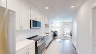 Located at 195 Mansfield Ave in Norton, MA, this thoughtfully designed one-bedroom, one-bathroom unit offers a clean, modern aesthetic with an efficient and functional layout. The open-concept living and kitchen area is anchored by warm hardwood flooring that runs throughout, creating a cohesive and inviting atmosphere. Large windows and a private exterior door fill the living room with natural light, while a wall-mounted mini-split system ensures year-round comfort.

The kitchen is well-appointed with crisp white shaker-style cabinetry extending to the ceiling, white subway tile backsplash, light quartz countertops, and a full suite of stainless steel appliances including a refrigerator, electric range, over-the-range microwave, and dishwasher. Recessed lighting illuminates the space efficiently.

The bedroom is a serene retreat featuring plush carpeting, a wall-mounted mini-split unit, and a window with natural light. A dedicated closet provides convenient storage.

The bathroom features classic black-and-white penny tile flooring, a white vanity with an undermount sink, and a shower-tub combination. Neutral wall tones throughout the unit lend a bright, airy feel that ties the entire space together cohesively.