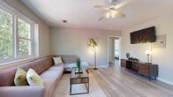 This single-story, 2-bedroom, 1-bathroom home offers a thoughtfully organized layout across a compact but functional floor plan. Light-toned wood-look flooring runs consistently throughout every room, lending a cohesive and clean aesthetic to the entire space.

The living room serves as the central gathering area, featuring a ceiling fan with light fixture, neutral gray walls, and windows that invite natural light. A dining area near the front entry provides additional versatility, with access to the main door and a side window for added brightness.

The kitchen is efficiently designed with white cabinetry extending to the ceiling for ample storage, a granite-look countertop, stainless steel sink, and a gas range with refrigerator included. Wood-look flooring continues here, maintaining visual continuity.

Both bedrooms are comfortably sized, each equipped with ceiling fans and windows overlooking greenery. The primary bedroom benefits from dual windows that fill the room with natural light, while the second bedroom offers a similarly serene atmosphere with soft neutral tones and framed wall art.

The hallways connect the rooms with ease, contributing to an intuitive flow throughout the home. The bathroom is clean and bright, featuring white tile wainscoting, a vanity with mirrored medicine cabinet, and classic white fixtures. Overall, the home presents a bright, modern, and move-in-ready living environment.