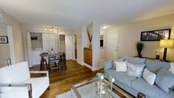 This upgraded 2-bedroom, 2-bathroom residence offers a well-designed single-level layout that maximizes comfort and functionality. The open-concept living and dining area serves as the heart of the home, anchored by warm hardwood flooring that flows seamlessly throughout the main living spaces. The living room provides a welcoming atmosphere with ample room for seating and relaxation, while the adjacent dining area accommodates a full dining set, ideal for everyday meals or entertaining guests. A partial wall divides the spaces subtly, adding architectural interest while maintaining an open feel. The kitchen is accessible directly from the dining area and features wood-toned cabinetry, offering generous storage and a practical workspace. A dedicated entry area with a storage cabinet provides a convenient transition into the home. The unit includes two well-proportioned bedrooms, each supported by its own full bathroom, offering privacy and ease of use. Closet space is thoughtfully integrated throughout. The textured ceilings and neutral wall tones create a clean, bright backdrop that complements the upgraded finishes. Overall, this residence combines classic design elements with modern upgrades to deliver a refined and livable space.