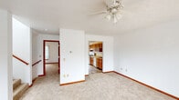 Located at 1311 Jack Pine Way in Kalamazoo, Michigan, this three-floor home offers a well-organized layout with consistent finishes throughout. The main living area features neutral carpet flooring, white walls with warm wood trim, and a ceiling fan with integrated lighting. Large windows dressed with vertical blinds invite natural light and provide outdoor views, creating a bright and open atmosphere. The kitchen is equipped with solid wood cabinetry in a warm honey tone, a double-basin stainless steel sink, a dishwasher, ample counter space, and a gas range — offering a practical and efficient workspace. Adjacent rooms on the main level provide additional flexible living areas. The bathrooms feature wood-framed vanity mirrors, medium-toned wood cabinetry with light countertops, and a combination of tile-style and wood-look flooring. One bathroom includes a window with vertical blinds for natural light, while another offers a tub-shower combination. A dedicated laundry room houses a full-size washer and dryer alongside wire shelving for storage. The upper levels include multiple carpeted bedrooms, each with vertical-blind windows providing natural light and outdoor views. Rich wood door and window trim is a consistent design element throughout, lending warmth and character to the home's interior.