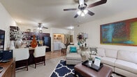 Located at 2401 SW Fireblaze Ave in Bentonville, AR, this single-floor, three-bedroom, one-bathroom residence offers a well-designed layout that maximizes functionality and comfort. The open-concept living area is bright and welcoming, featuring ceiling fans, neutral walls, and windows dressed with blinds that allow natural light to filter in. The living room provides generous room for seating and entertaining, flowing seamlessly into the kitchen and dining area. The kitchen is a standout feature, equipped with rich dark wood cabinetry, granite-style countertops, a full suite of black appliances including a refrigerator, range, microwave, and dishwasher, and durable hardwood-style flooring. Each of the three bedrooms is carpeted for warmth and comfort, fitted with ceiling fans, and includes windows for natural light. The primary bedroom offers a comfortable, well-proportioned retreat. The shared bathroom includes a tub/shower combo with sliding glass doors, dark wood cabinetry for storage, and hardwood-style flooring. A dedicated laundry area houses a full-size washer and dryer with built-in wire shelving above for additional storage. A hallway and closet round out the practical layout of this efficiently designed home.