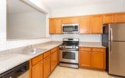 Located at 2800 New Brunswick Ave in Piscataway, NJ, this single-floor residence offers a clean, functional layout designed for comfortable everyday living. The open entryway welcomes you into a spacious living area finished with light hardwood-style flooring and soft neutral-toned walls, creating a bright and airy atmosphere. A pass-through opening connects the living space seamlessly to the kitchen, which is outfitted with warm honey-toned cabinetry, granite-style countertops, a classic subway tile backsplash, and a full suite of stainless steel appliances including a gas range, over-the-range microwave, and refrigerator. Light tile flooring completes the kitchen's practical design. The bedrooms are carpeted and bathed in natural light from large windows fitted with blinds, offering a quiet and restful environment. Two bathrooms serve the residence — one featuring a tub-shower combination with sliding glass doors and a wood-cabinet vanity, and a larger bathroom with a spacious vanity and a separate glass-enclosed shower. A dedicated in-unit laundry area houses a full-size washer and dryer, adding everyday convenience. Throughout, the residence maintains a cohesive, neutral palette that provides a versatile and move-in-ready living environment.