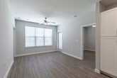 This single-floor unit offers a clean, contemporary design throughout, with light-toned luxury vinyl plank flooring and neutral gray-white walls creating a bright, cohesive aesthetic. The open-concept kitchen is a central highlight, featuring white shaker-style cabinetry extending to the ceiling for ample storage, granite-look countertops, and a full suite of stainless steel appliances including a range, over-the-range microwave, dishwasher, and refrigerator. Recessed lighting illuminates the kitchen efficiently.

A hallway connects the kitchen to the living area, which is generously sized and filled with natural light from large windows fitted with horizontal blinds. A ceiling fan provides additional comfort in this open space, which also provides access to an outdoor area.

The unit includes two bedrooms, each equipped with ceiling fans and windows with blinds that allow for natural light while maintaining privacy. Both bathrooms follow a consistent design language, featuring white tiled tub and shower combinations, granite-topped vanities with drawer storage, and clean, neutral finishes throughout. The overall ambiance is modern, move-in ready, and well-suited for comfortable everyday living.