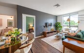 This thoughtfully designed two-bedroom, two-bathroom residence at 275 Washington Street in Newton, MA offers a refined modern living experience across a well-appointed single floor. The open-concept layout seamlessly connects the kitchen, dining, and living areas, creating a welcoming, fluid space ideal for everyday living and entertaining.

The kitchen is a standout feature, showcasing quartz countertops, a center island with bar seating, light wood lower cabinetry, crisp white upper cabinets, and stainless steel appliances. Rich hardwood flooring flows throughout the main living areas, adding warmth and continuity.

The living room is bright and inviting, with large windows framing lush treetop views. A bold accent wall in charcoal gray adds depth and a contemporary edge to the space.

The primary bedroom offers a serene retreat with hardwood floors, generous natural light, and a neutral palette. The second bedroom features a distinctive sage green accent wall and large windows, making it a versatile space suitable as a guest room or home office.

Both bathrooms are finished with clean, modern aesthetics — one featuring hexagonal tile flooring and a light wood vanity, and the other with a sleek glass-enclosed walk-in shower and coordinating hex tile floors. Every detail reflects a commitment to quality and contemporary design.