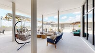 Located at 2479 NE 192nd St in Miami, FL, this rooftop amenity terrace offers a sophisticated blend of indoor-outdoor living designed for relaxation and social gatherings. The space is characterized by soaring ceilings within its covered interior lounge, supported by clean structural columns and finished with large-format light-toned tile flooring that extends seamlessly throughout both indoor and outdoor areas.

The interior covered lounge is generously proportioned, featuring an eclectic mix of seating arrangements including wicker-framed sofas with plush white cushions, a standout hanging egg chair, and wood-accented coffee tables. Floor-to-ceiling glass walls and expansive openings connect this interior zone directly to the open-air terrace, flooding the space with abundant natural light and offering unobstructed views of the Miami skyline and surrounding treetops.

The outdoor terrace is divided into multiple functional zones: a shaded pergola area with a warm wood-lattice overhead structure hosts bar-height tables and casual lounge seating, while open sun decks provide additional seating arrangements with teal and neutral-toned furnishings. A dedicated outdoor dining area with tables and chairs offers an al fresco setting beneath the open sky.

A wraparound perimeter deck provides panoramic views, and a water fountain station adds a practical amenity touch. The overall design aesthetic is modern and airy, combining neutral tones, natural wood accents, and lush greenery to create a refined, resort-inspired rooftop experience.