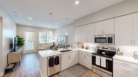 Located in Scottsdale, AZ, this thoughtfully designed one-bedroom, one-bathroom residence offers a modern, cohesive aesthetic with a neutral color palette and clean lines throughout. The open-concept kitchen and living area serves as the heart of the home, featuring sleek white cabinetry, quartz countertops, stainless steel appliances, and stylish pendant lighting. A peninsula with bar seating provides a casual dining option, while the adjoining living space benefits from a glass door and large windows that invite natural light and outdoor views. Wood-look flooring extends across the main living area, adding warmth and continuity. The bedroom is a comfortable retreat, finished with soft carpet, a ceiling fan, and a well-sized window that allows additional natural light. Neutral wall tones and subtle décor create a calm and restful atmosphere. The dedicated closet offers practical storage. The bathroom is clean and modern, featuring a white vanity with quartz countertop, wood-look flooring, and a glass-enclosed walk-in shower with white tile surround. A hallway connects the spaces efficiently, contributing to a logical and functional floor plan. This single-floor residence in Scottsdale combines contemporary design with everyday practicality.