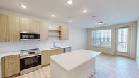 Located on W Mallard Creek Church Rd in Charlotte, NC, this one-bedroom, one-bathroom unit offers a thoughtfully designed single-floor layout with a clean, contemporary aesthetic. Light wood-look flooring runs throughout, complementing the bright, neutral color palette that gives the space an open and airy feel.

The kitchen is a standout feature, showcasing flat-front cabinetry in a warm natural wood tone paired with white quartz countertops and a subway tile backsplash. A large central island provides ample prep space and casual seating potential. Stainless steel appliances — including a refrigerator with French doors, a range, microwave, and dishwasher — complete the well-equipped cooking space. Recessed lighting illuminates the area effectively.

The bedroom is generously sized, featuring a ceiling fan with light fixture and a window that allows natural light to filter in. An adjacent walk-in closet offers multi-tier wire shelving along the walls, providing organized and practical storage.

The bathroom includes a full tub-shower combo with clean white tile surround, a wood-toned vanity with white countertop, and recessed lighting, maintaining the same modern and cohesive design language found throughout the unit. The overall layout is efficient and well-planned, making excellent use of the available space.