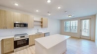 Located on W Mallard Creek Church Rd in Charlotte, NC, this one-bedroom, one-bathroom unit offers a thoughtfully designed single-floor layout with a clean, contemporary aesthetic. Light wood-look flooring runs throughout, complementing the bright, neutral color palette that gives the space an open and airy feel.

The kitchen is a standout feature, showcasing flat-front cabinetry in a warm natural wood tone paired with white quartz countertops and a subway tile backsplash. A large central island provides ample prep space and casual seating potential. Stainless steel appliances — including a refrigerator with French doors, a range, microwave, and dishwasher — complete the well-equipped cooking space. Recessed lighting illuminates the area effectively.

The bedroom is generously sized, featuring a ceiling fan with light fixture and a window that allows natural light to filter in. An adjacent walk-in closet offers multi-tier wire shelving along the walls, providing organized and practical storage.

The bathroom includes a full tub-shower combo with clean white tile surround, a wood-toned vanity with white countertop, and recessed lighting, maintaining the same modern and cohesive design language found throughout the unit. The overall layout is efficient and well-planned, making excellent use of the available space.