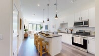 Located at 112 Bilby Road in Hackettstown, NJ, this thoughtfully designed one-bedroom, one-bathroom residence offers a modern aesthetic with high-quality finishes throughout. The open-concept kitchen and living area serves as the heart of the home, featuring white shaker cabinetry, dark countertops, a mosaic tile backsplash, stainless steel appliances, and a central island with bar seating illuminated by sleek pendant lighting. Wide-plank hardwood-style flooring flows seamlessly throughout the space, enhancing its contemporary feel. The living area is bathed in natural light from large black-framed windows and a bold accent wall, creating an inviting and stylish atmosphere. The well-proportioned bedroom includes a ceiling fan, a sliding glass door leading to a private balcony with outdoor views, and access to three closets offering ample storage. In-unit stacked laundry is conveniently accessible from the bedroom. The bathroom is finished with a white vanity, dark countertop, backlit mirror, and a tiled tub-shower combination with matte black fixtures. The private balcony extends the living space outdoors, completing this well-appointed and efficiently laid-out home.