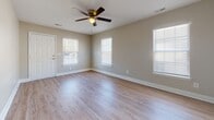 Located at 7900 Rocky Mount Rd in North Charleston, SC, this single-story home offers a clean, modern aesthetic throughout its thoughtfully designed layout. The open living area welcomes you with light-toned wood-look luxury vinyl plank flooring, neutral warm-gray walls, and a ceiling fan that enhances the bright, airy feel of the space. Multiple windows dressed with white horizontal blinds invite natural light while maintaining privacy.

The kitchen is well-equipped, featuring white shaker-style cabinetry extending to the ceiling for generous storage, granite-look countertops, a stainless steel sink, a dishwasher, and a full-size refrigerator. The kitchen opens directly toward the main living area, creating a connected and functional flow.

The bedrooms are carpeted for comfort and each include ceiling fans and ample natural light from well-positioned windows. Closet space is plentiful, with multiple bedroom closets featuring built-in shelving and hanging rods. The bathrooms are finished with wood-look flooring and include full tub-shower combinations with tiled surrounds and chrome fixtures, maintaining a consistent, clean design throughout.

The overall ambiance of the home is fresh and move-in ready, with a cohesive neutral palette that offers a versatile backdrop for any style of living.
