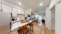 Located at 4502 W McCoy St in Tampa, FL, this thoughtfully designed single-story residence offers a seamless open-concept layout that connects the kitchen, dining, and living areas into one cohesive and functional space. Light-toned luxury vinyl plank flooring runs throughout, complementing the clean, contemporary aesthetic.

The kitchen is a standout feature, outfitted with two-tone shaker-style cabinetry, white quartz countertops, a subway tile backsplash, and a full suite of stainless steel appliances. A central island with bar seating provides additional prep space and a casual dining option, making the kitchen both practical and inviting.

The living room is bright and welcoming, benefiting from natural light streaming through a full-length glass door that opens to a private outdoor area. A ceiling fan, sheer drapes, and tasteful wall paneling details lend the space a relaxed yet polished character.

The bedroom is generously sized, featuring large windows that flood the room with natural light, a ceiling fan, and a calm, neutral color palette accented by a rich slate-toned feature wall. It connects directly to a well-designed bathroom with a wide quartz vanity, modern fixtures, ample cabinetry, and access to a spacious walk-in closet, completing this comfortable and well-appointed home.
