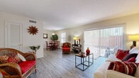 Located at 102 Jamestown Dr in Winter Park, Florida, this single-story residence offers a well-organized layout designed for comfortable living. The main living area is open and airy, featuring wood-look plank flooring that extends throughout much of the home. Large sliding glass doors dominate one wall of the living room, allowing abundant natural light to flow in while providing direct access to a private outdoor patio enclosed by a wood fence.

The dining area sits adjacent to the living space, benefiting from a dedicated window fitted with white horizontal blinds that allow for controlled natural light. A pendant light fixture overhead completes this functional dining nook. The kitchen features warm-toned wood cabinetry, a white range, and durable flooring, with a louvered pantry door adding a classic touch.

A hallway connects the living spaces to the bedroom, which is carpeted and offers a peaceful retreat with windows, a louvered closet, and ample room. The full bathroom includes a tub-shower combination with tile surround, a vanity with a white countertop, and wood-look flooring. Throughout the home, neutral wall tones and consistent finishes create a cohesive, inviting ambiance.