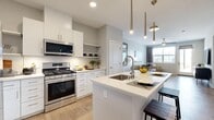 This well-appointed 2-bedroom, 2-bathroom single-floor residence offers a thoughtfully designed open-concept layout that maximizes both functionality and comfort. The kitchen serves as a central showpiece, featuring crisp white cabinetry, stainless steel appliances including a gas range and refrigerator, white quartz countertops with a subway tile backsplash, open shelving, and a large island with an undermount sink and seating — ideal for casual dining and entertaining. Sleek pendant lighting with brass accents adds a modern touch overhead.

The living room flows naturally from the kitchen, bathed in natural light from large windows dressed with contemporary blinds and curtains. A ceiling fan adds to the comfort of the space, which features light hardwood-style flooring throughout the main areas.

The spacious primary bedroom offers a serene retreat with plush carpet, generous proportions, and access to a dedicated closet with built-in shelving. The second bedroom is bright and comfortable, with large windows framing outdoor greenery. Both bathrooms are finished with white vanities, quartz countertops, and wood-style tile flooring — one featuring a tub/shower combo and the other a walk-in shower. A hallway connects all rooms efficiently, completing this cohesive and modern floor plan.