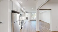 This well-appointed 1-bedroom, 1-bathroom unit offers a thoughtfully designed single-floor layout with a clean, contemporary aesthetic throughout. The open-concept kitchen and living area serves as the heart of the unit, featuring sleek white cabinetry extending to the ceiling, stainless steel appliances including a refrigerator, electric range, built-in microwave, and dishwasher, complemented by light countertops and a single-basin sink. Recessed lighting illuminates the space, while warm wood-look flooring flows seamlessly through every room, adding a sense of continuity and warmth.

The living area is bright and airy, with large floor-to-ceiling windows that invite abundant natural light and provide views of the surrounding neighborhood and greenery. The bedroom offers a comfortable and serene retreat, also benefiting from natural light through a well-placed window and featuring a dedicated closet space. The hallways connect the rooms efficiently, contributing to the unit's functional flow.

The bathroom is finished with marble-style tile in the tub/shower surround, pairing well with the clean white walls. An in-unit laundry area with a stacked washer and dryer adds everyday convenience. The overall ambiance is modern, bright, and move-in ready.