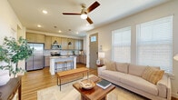 This two-story home offers a thoughtfully designed layout spread across two floors, with the larger main floor housing the primary living spaces and the upper level dedicated to more intimate quarters. The main floor features an open-concept design where the kitchen flows seamlessly into the living area. The kitchen is equipped with stainless steel appliances, warm wood cabinetry, granite countertops, a tile backsplash, and a central island with bar seating illuminated by pendant lighting. Hardwood-style flooring runs throughout the main level, complementing the neutral color palette and recessed lighting. A ceiling fan enhances the airy feel of the living space, which benefits from natural light through multiple windows. A second living area upstairs features soft carpet, a sage green accent wall, and additional window light, offering a versatile flex space. The primary bedroom includes hardwood-style flooring, a bold accent wall, a ceiling fan, and a natural-light-filled window. Additional bedrooms are carpeted and bright. Both bathrooms feature wood-toned vanities and tub-shower combinations. The attached garage provides ample storage and parking space, completing this well-organized home.