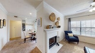 This single-floor residence offers a thoughtfully designed open-concept layout that seamlessly connects the living, dining, and kitchen areas. The carpeted living room serves as the heart of the home, anchored by a classic white-mantled wood-burning fireplace and accented by crown molding. A ceiling fan and wide windows allow natural light to fill the space, creating a bright and comfortable atmosphere.

The galley-style kitchen is equipped with dark wood cabinetry, light stone-look countertops, stainless steel appliances including a refrigerator and electric range, a double sink, and track lighting overhead. Wood-look flooring adds a warm, durable touch to this functional cooking space. A half-wall peninsula connects the kitchen to the living area, enhancing the open feel.

The dining area is positioned adjacent to a sliding glass door that opens to a private balcony, flooding the space with natural light and offering outdoor views. A large mirror further amplifies the sense of space.

The bedroom is comfortably sized with plush carpet and a window with outdoor views. The bathroom features an extended dual-sink vanity with stone countertops, dark wood cabinetry, a large mirror, and wood-look tile flooring. A dedicated laundry area with a top-loading washer, dryer, and wire shelving rounds out the practical features of this well-equipped residence.
