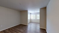 Located at 100 Lochaven Dr in Charleston, SC, this single-floor, one-bedroom, one-bathroom residence offers a practical and well-organized layout. The open living area is divided into two connected zones, both finished with rich, dark hardwood-style flooring and neutral gray walls that create a clean, cohesive aesthetic. Large windows fitted with white blinds allow natural light to fill the space, adding warmth and openness to the interior.

The kitchen is thoughtfully designed with crisp white shaker-style cabinetry, dark granite-look countertops, and a full suite of black appliances including a range, microwave, dishwasher, and refrigerator. Hardwood-style flooring continues throughout, tying the kitchen seamlessly into the main living areas.

The bedroom is a comfortable, well-proportioned room featuring soft carpeting, a ceiling fan with light fixture, a window for natural light, and direct access to a dedicated closet. The bathroom is equipped with a full tub-shower combination, a white vanity with dark countertop, and hardwood-style flooring that mirrors the rest of the home.

A hallway connects the private areas of the residence to the main living spaces, providing a clear and functional flow throughout. The overall design is neutral, clean, and move-in ready.