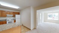 This single-floor residence offers a thoughtfully designed layout that balances functionality and comfort. The kitchen is a standout feature, equipped with warm honey-toned cabinetry, granite countertops, a peninsula with breakfast bar seating, and white appliances including a range, refrigerator, and dishwasher. Tile flooring in the kitchen transitions smoothly into the carpeted living area, which receives natural light through large windows that provide views of the surrounding outdoor environment.

The bedrooms are generously sized, each finished with plush carpet and windows that invite natural light. The primary bedroom includes a walk-in closet with built-in shelving for ample storage, along with access to a private en-suite bathroom. The en-suite features a single-sink vanity with wood cabinetry and a glass-enclosed shower stall. A second full bathroom serves the remaining rooms and includes a vanity with matching cabinetry and a combination tub-shower unit.

Throughout the unit, neutral wall tones and clean white trim create a bright, move-in-ready atmosphere. The open connection between the kitchen and living areas supports a versatile and practical floor plan suitable for a range of living arrangements.