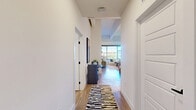 Located at 550 Westlake Park Blvd in Houston's Westlake area, this thoughtfully designed one-bedroom, one-bathroom residence offers a well-appointed layout across a single floor. The open-concept kitchen and living area serves as the heart of the home, where the kitchen impresses with two-tone cabinetry in white and slate blue, quartz countertops, a central island with seating, stainless steel appliances, a subway tile backsplash, and pendant lighting — all set atop warm hardwood-style flooring. The living room is bathed in natural light from expansive floor-to-ceiling windows that frame outdoor treetop views, and features an exposed industrial-style ceiling with a ceiling fan, adding a contemporary loft aesthetic. The spacious bedroom offers a comfortable retreat with large windows, exposed ductwork as a design element, plush carpeting, and a dedicated workspace area. The bathroom is finished with marble-style tile in a walk-in glass-enclosed shower, wood-look flooring, and modern matte black fixtures. A dedicated laundry room with a full-size washer and dryer adds everyday convenience. A hallway and closet complete the efficient and functional floor plan.