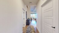 Located at 550 Westlake Park Blvd in Houston's Westlake area, this thoughtfully designed one-bedroom, one-bathroom residence offers a well-appointed layout across a single floor. The open-concept kitchen and living area serves as the heart of the home, where the kitchen impresses with two-tone cabinetry in white and slate blue, quartz countertops, a central island with seating, stainless steel appliances, a subway tile backsplash, and pendant lighting — all set atop warm hardwood-style flooring. The living room is bathed in natural light from expansive floor-to-ceiling windows that frame outdoor treetop views, and features an exposed industrial-style ceiling with a ceiling fan, adding a contemporary loft aesthetic. The spacious bedroom offers a comfortable retreat with large windows, exposed ductwork as a design element, plush carpeting, and a dedicated workspace area. The bathroom is finished with marble-style tile in a walk-in glass-enclosed shower, wood-look flooring, and modern matte black fixtures. A dedicated laundry room with a full-size washer and dryer adds everyday convenience. A hallway and closet complete the efficient and functional floor plan.