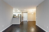This single-floor residence offers a thoughtfully designed layout that balances comfort and functionality throughout. The open living area is anchored by rich, dark hardwood flooring that extends seamlessly through the main spaces, complemented by warm neutral-toned walls and clean white baseboards. A glass-paned door leads to a private balcony, filling the living area with natural light and providing outdoor views.

The galley-style kitchen is efficiently laid out and features stainless steel appliances, including a refrigerator, gas range, built-in microwave, and dishwasher. White cabinetry with ample storage and granite-style countertops complete the functional and clean aesthetic. A peninsula counter opens the kitchen toward the main living area, enhancing the sense of connectivity.

The bedrooms are carpeted for comfort and each receives natural light through sizable windows fitted with blinds. One bedroom includes access to a walk-in closet, offering generous storage. The two bathrooms are finished with hardwood-style flooring, white vanities, and standard fixtures — one featuring a shower with curtain, the other a full soaking tub with shower combination. The overall design is clean, neutral, and move-in ready.