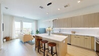 Located in Nashville, TN, this thoughtfully designed one-bedroom, one-bathroom residence offers a modern, open-concept layout across a single floor. The combined kitchen and living area serves as the heart of the space, featuring light wood flooring that flows throughout and an abundance of natural light. The contemporary kitchen is outfitted with flat-front light wood cabinetry, under-cabinet lighting, white quartz countertops, stainless steel appliances including a French door refrigerator, electric range, and built-in microwave, and a central island with bar seating — ideal for both cooking and casual dining. The living area opens directly to a private balcony through large glass doors, offering elevated views of the surrounding Nashville cityscape. The bedroom is generously proportioned, featuring a large picture window with the same urban views, light wood flooring, and a closet. The bathroom is clean and modern, with light wood vanity cabinetry, a sleek white countertop, large-format tile flooring, and an in-unit washer conveniently integrated above the vanity. Throughout the space, a consistent palette of warm woods, white finishes, and neutral tones creates a cohesive and contemporary ambiance.
