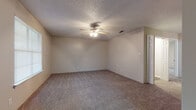 This single-floor residential unit offers a practical and well-organized layout designed for comfortable everyday living. The space includes multiple bedrooms, each finished with plush wall-to-wall carpeting and ceiling fans with integrated light fixtures, providing both comfort and air circulation. Several bedrooms feature windows fitted with horizontal blinds, allowing natural light to filter in while maintaining privacy. The walls throughout are finished in neutral beige tones, complemented by textured popcorn ceilings that add a classic touch to the interior.

The kitchen is equipped with gray cabinetry, dark speckled countertops, a stainless steel double sink, a black refrigerator, a dishwasher, and a range, offering ample storage and prep space. Light wood-look flooring runs through the kitchen and wet areas, providing a durable and easy-to-clean surface. A built-in shelving closet adjacent to the kitchen serves as a convenient pantry or storage area.

The bathroom includes a full tub and shower combination with tile surround, a vanity with dark countertop and undermount sink, and light wood-look flooring, keeping the space clean and cohesive. Overall, the unit presents a straightforward, functional design well-suited for a variety of living arrangements.