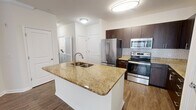 This 680 square foot apartment in West Chester, PA, offers a thoughtful blend of modern amenities and efficient design. The single-floor layout comprises one bedroom, one bathroom, and an open-concept kitchen and living area. The primary bedroom, measuring 170 square feet, provides ample space and features plush carpeting and a ceiling fan for comfort.

The kitchen is a highlight, boasting dark wood cabinetry contrasting beautifully with stainless steel appliances and a subway tile backsplash. A large granite-topped island serves as both a workspace and casual dining area. The adjoining living room features hardwood flooring and large windows, allowing natural light to flood the space.

The bathroom is appointed with a modern vanity, offering ample storage and a large mirror. Throughout the apartment, neutral wall colors create a bright, airy atmosphere. The unit also includes a hallway and a closet, enhancing storage options.

Attention to detail is evident in the crown molding and baseboards that adorn the rooms. The combination of carpeting in the bedroom and hardwood in the living areas adds texture and warmth to the space. With its clever use of space and contemporary finishes, this apartment offers comfortable urban living in a compact footprint.