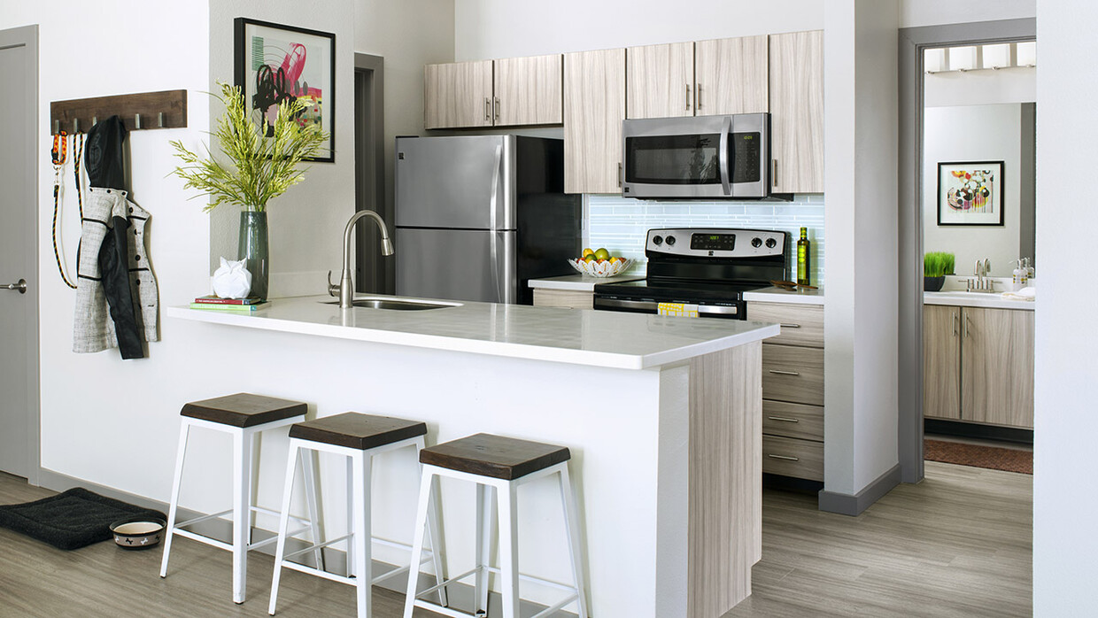 Cocina del apartamento con electrodomésticos de acero inoxidable, encimeras de cuarzo y suelos de madera. - Griffis Belleview Station