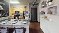 Located at 4050 Rocky Circle in Tampa, FL, this single-story unit showcases an industrial-inspired design with polished concrete floors, exposed ductwork, and dark trim throughout the common areas. The living room is bright and welcoming, featuring large windows with blinds that allow ample natural light, wall-mounted shelving, and a direct entry door — giving the space an open, loft-like character.

The kitchen is efficiently designed with warm maple cabinetry, dark countertops, black appliances including a range and refrigerator, and a peninsula with seating — ideal for casual dining or entertaining. A dedicated entry corridor connects the main living areas seamlessly.

Multiple bedrooms provide private, carpeted retreats, each with windows that bring in natural light, ceiling fans, and sufficient space for a bed and study area. The rooms offer versatility for a range of living arrangements. Each bedroom is paired with its own private bathroom, fitted with wood-tone vanity cabinetry, granite-style countertops, wood-look tile flooring, a large mirror with overhead lighting, and a shower-tub combination with stone-patterned tile surround. This unit combines practical functionality with a modern urban aesthetic, making it well-suited for student or young professional living near Tampa's University of South Florida corridor.