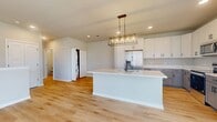 This contemporary 1-bedroom apartment in Elgin, IL, spans 910 square feet across two floors, offering a seamless blend of style and functionality. The main living area boasts an open-concept design, combining the kitchen and living room for a spacious feel. Large windows and a balcony door flood the space with natural light, while providing picturesque views of the surrounding area.

The kitchen is a highlight, featuring sleek white cabinetry, contrasting lower cabinets, and modern stainless steel appliances. A generously sized island with a light-colored countertop serves as both a prep area and casual dining space. The living room, with its hardwood flooring, offers ample space for relaxation and entertainment.

The bedroom, measuring 170 square feet, is carpeted for comfort and includes a large window for natural illumination. The bathroom is pristine, with a modern white aesthetic, featuring a bathtub-shower combination and ample storage space.

Throughout the apartment, neutral tones create a calm ambiance, while the abundance of windows ensures a bright, airy atmosphere. The two-floor layout, with 70 square feet on the ground floor and 840 square feet on the upper level, adds architectural interest and separates living spaces effectively.